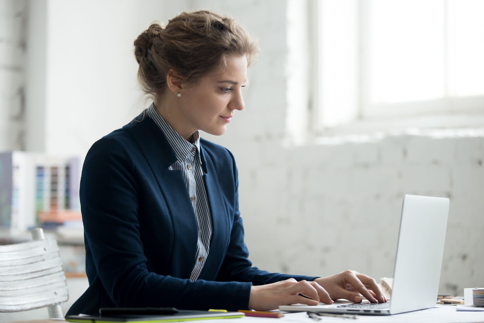 A woman in a suit works at her laptop